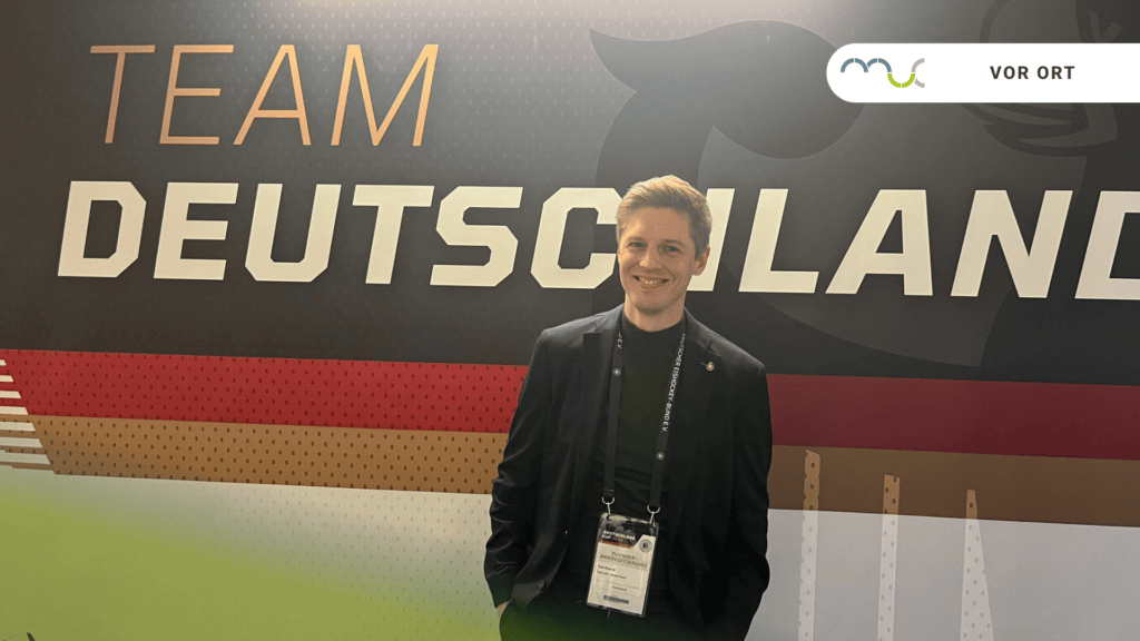 Sportpsychologe Dr. Tom Kossak steht vor einem Banner mit der Aufschrift "Team Deutschland"